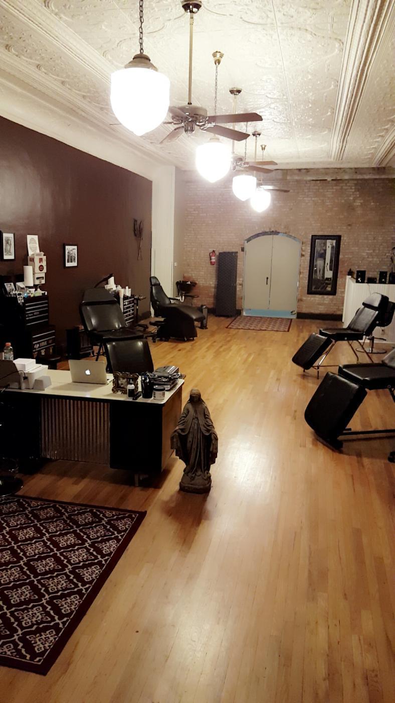 The studio floor: pressed tin ceiling, exposed brick wall, wood boards and three tattoo chairs