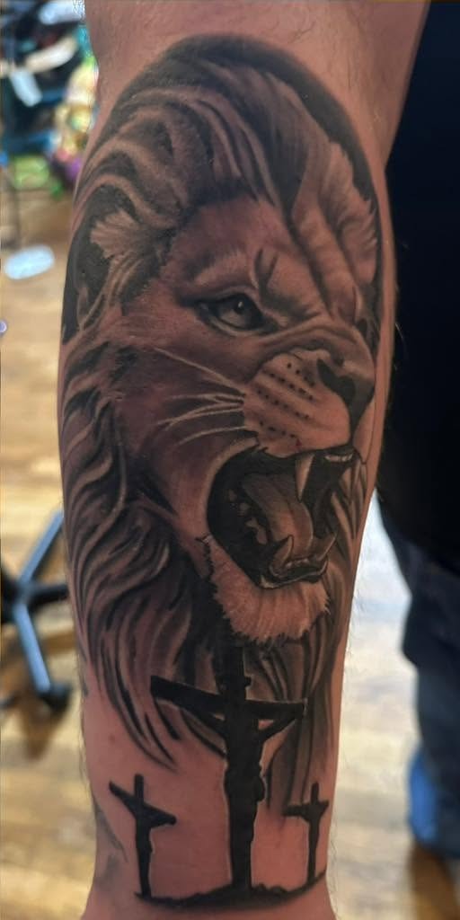 Black and gray roaring lion above three crosses, on an arm